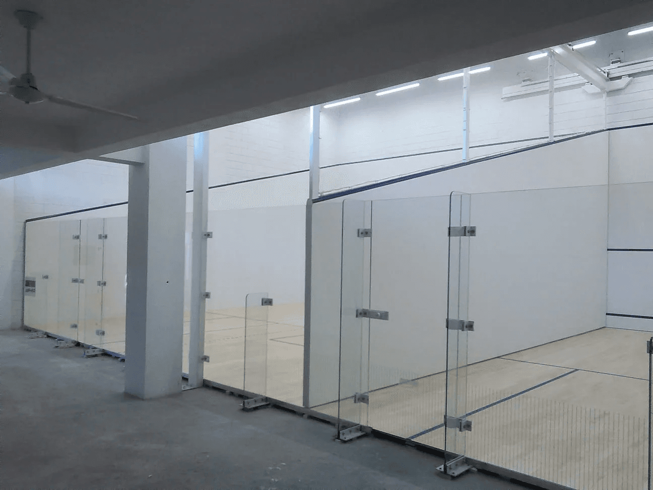Squash court with three-sided glass and white play walls