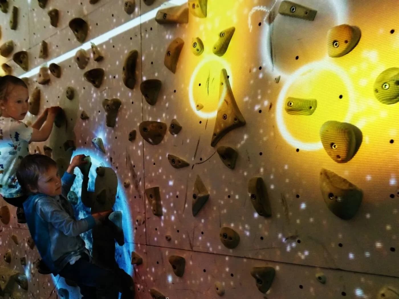 Children playing an interactive projected game on an Augmented Climbing Wall